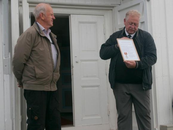 Arnstein Hansen overrakte medaljen innrammet og med litt skriftlig historikk til Skålvær kirke, her representert ved Nils Falch.