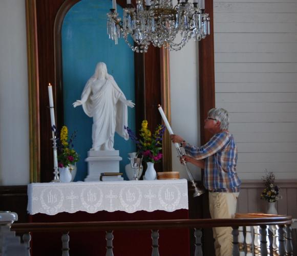 Klar for jubileumsgudstjeneste. Gunhild setter p� plass lysene. Alteret pyntet med markblomster som vanlig.